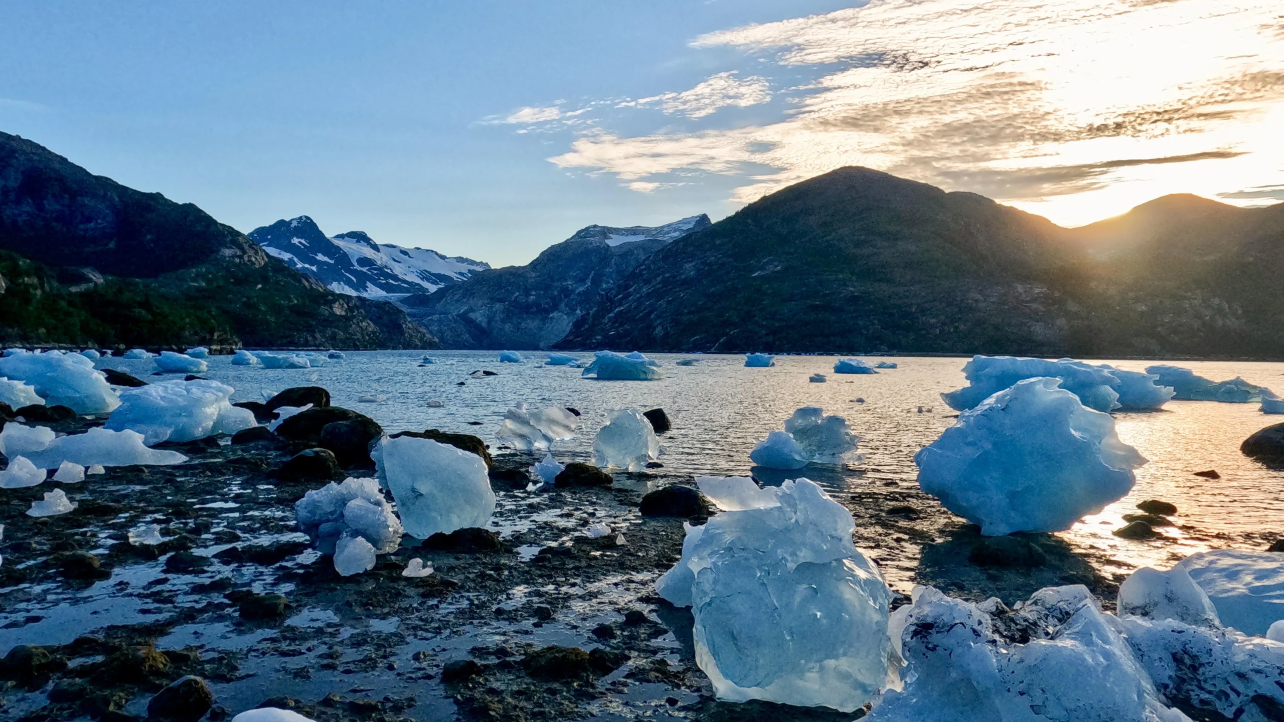 pieces of iceberg on a beach at sunset