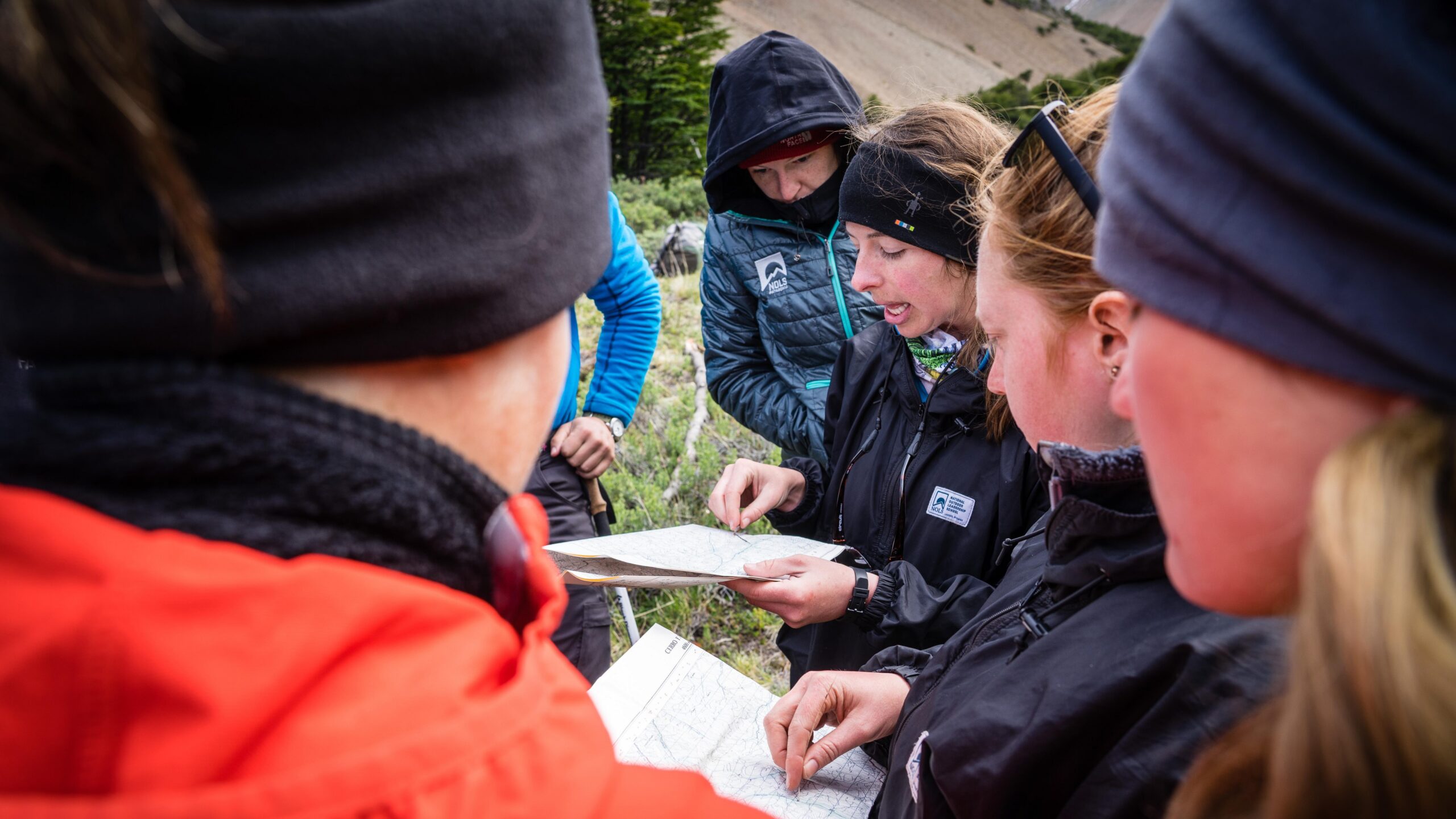 a woman surrounded by other faces looks at a map and talks