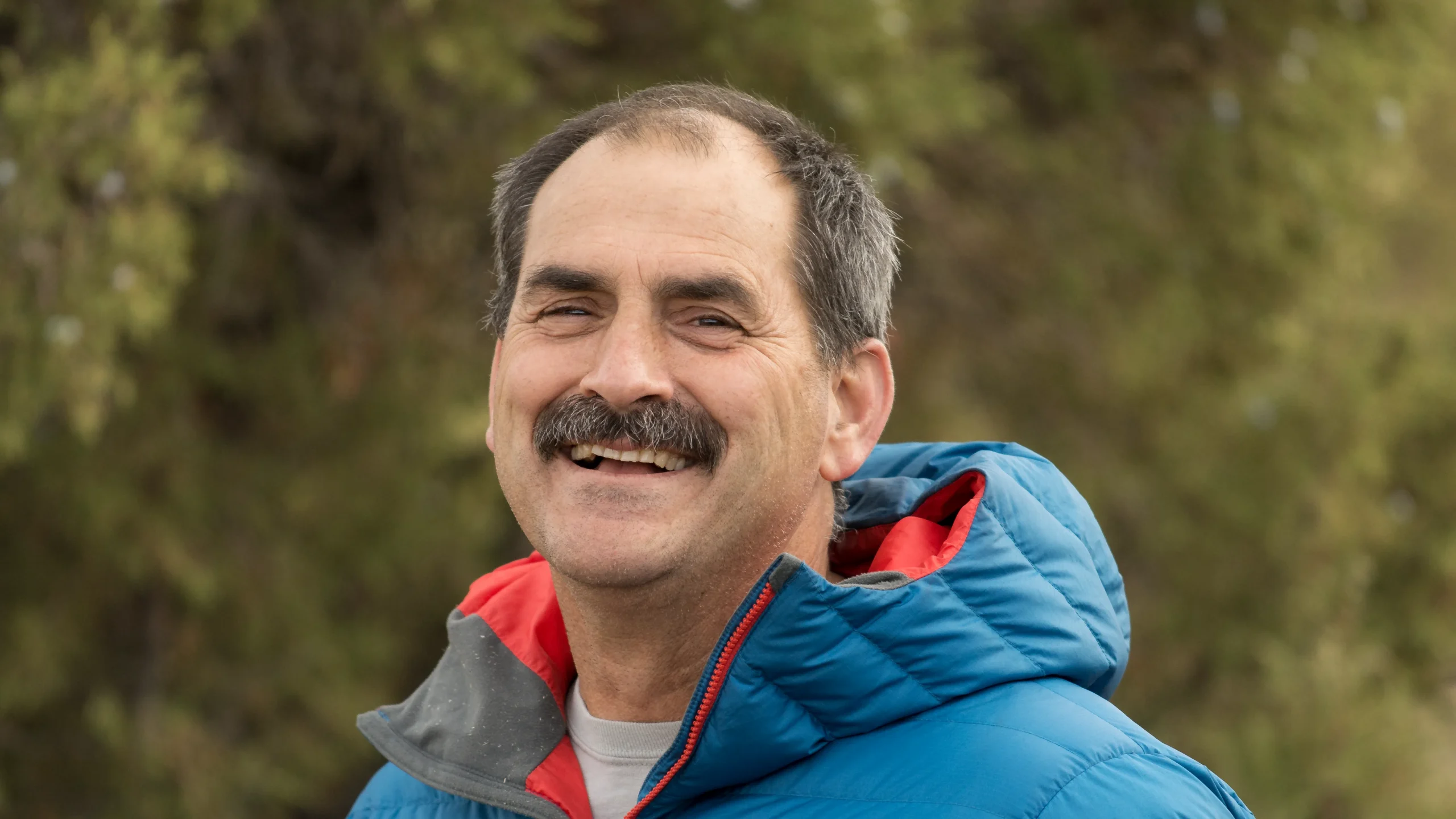 a man with a mustache smiles at the camera